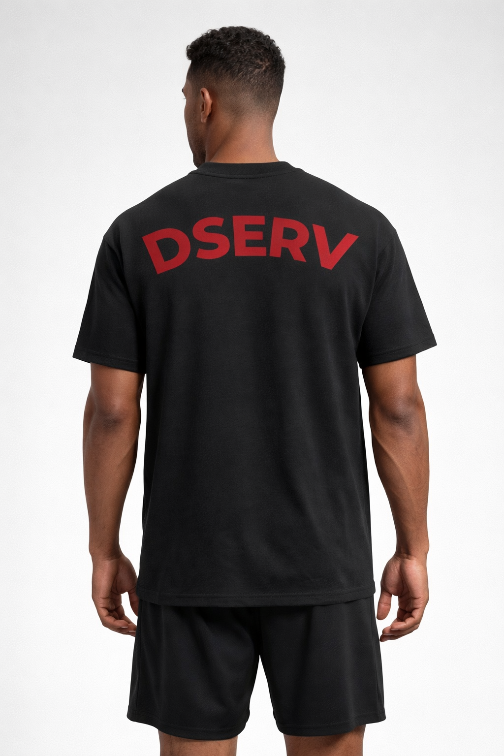 Person wearing a black t-shirt with 'DSERV' printed on the back against a white background