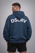 Man wearing an Airforce blue hoodie with 'DSERV' printed on the back against a gray background