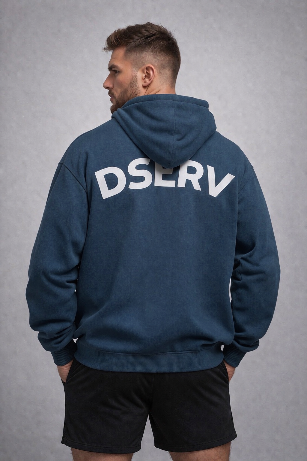 Man wearing an Airforce blue hoodie with 'DSERV' printed on the back against a gray background