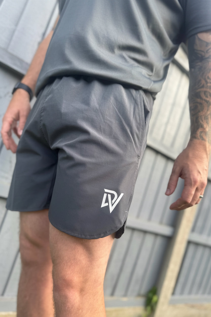 Male wearing grey performance running shorts with a DV logo