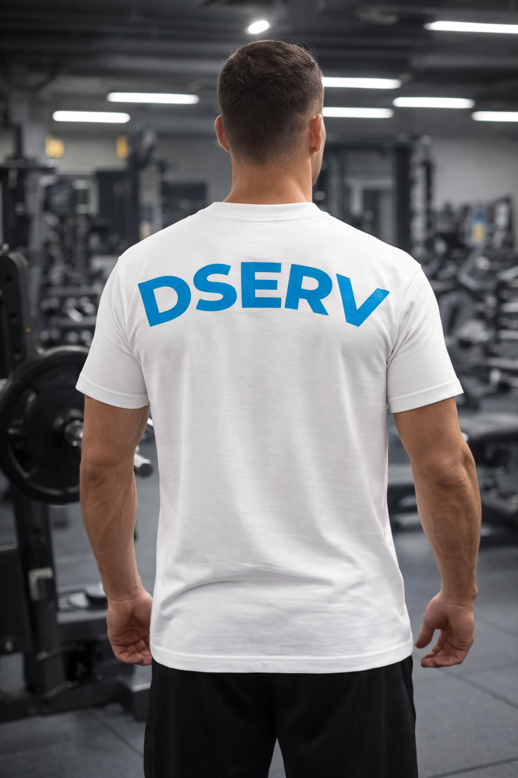 Person wearing a white t-shirt with 'DSERV' printed on the back in a gym setting