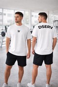 Two men wearing white t-shirts with logos, one facing forward and one facing backward, in a gym setting.