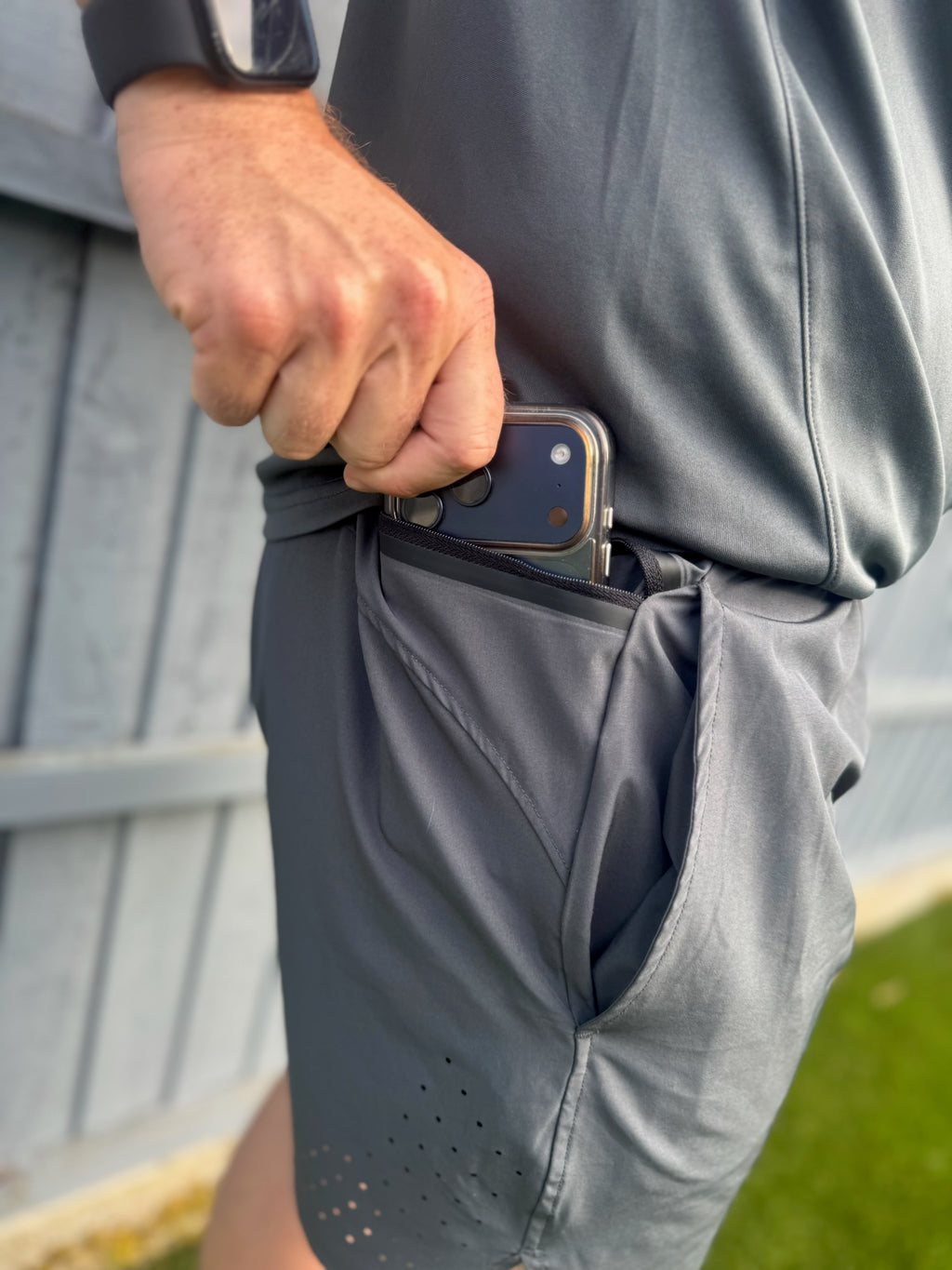 Man putting mobile phone into secure side drop pockets with a zip