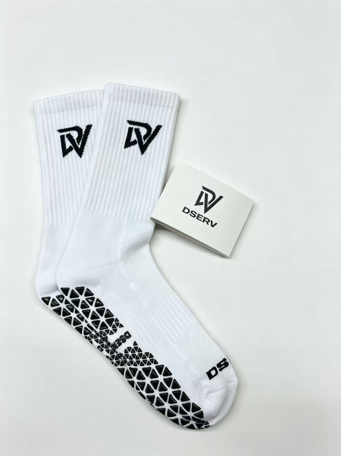White crew socks with DV branding and black textured rubber soles for grip