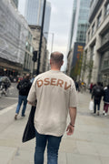 Male weating a Stone Oversized Tshirt in a city setting with DSERV across the shoulders