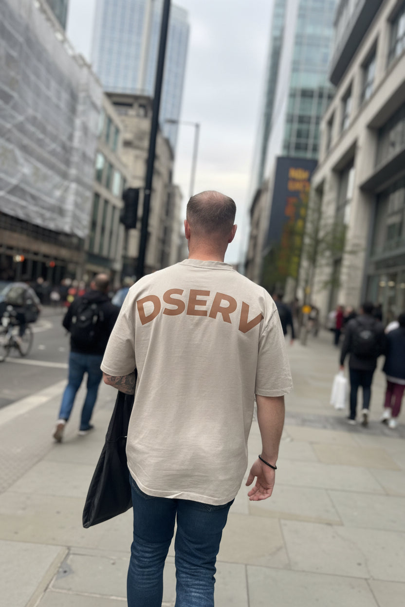 Male weating a Stone Oversized Tshirt in a city setting with DSERV across the shoulders