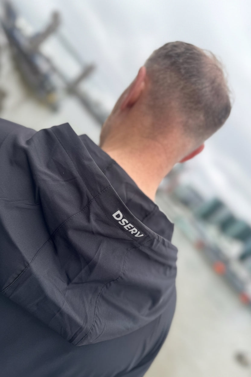 Person wearing a dark jacket with 'Dserv' branding in an outdoor setting.