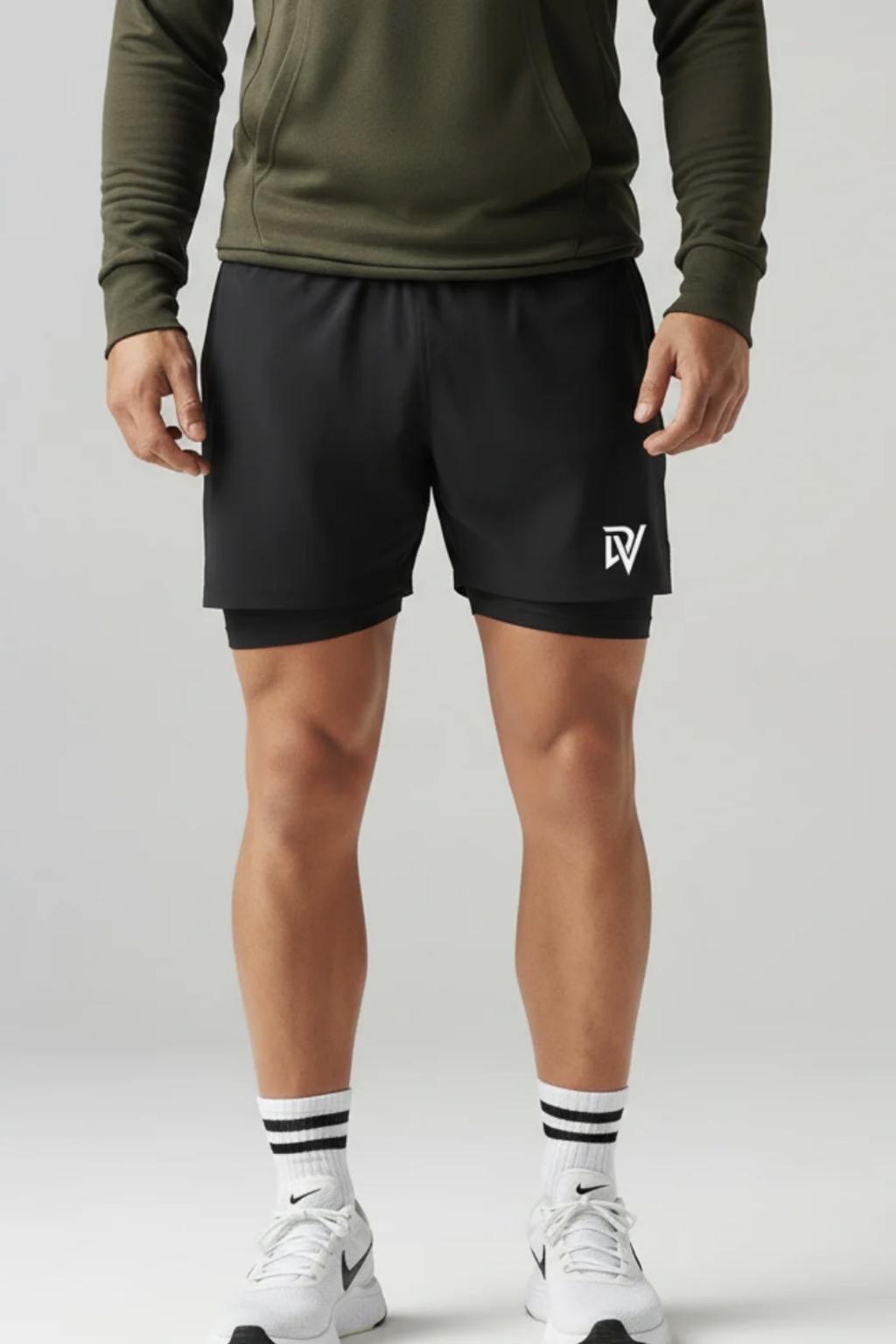 Person wearing black shorts with a logo, green long-sleeve shirt, and white sneakers on a light gray background